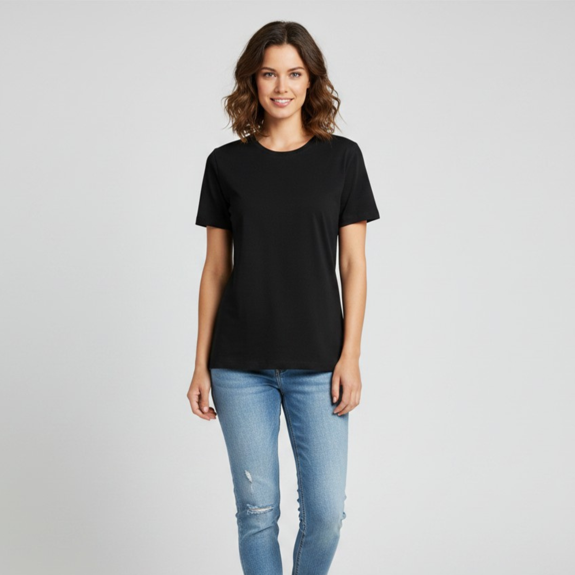 Woman wearing a black t-shirt and blue jeans on a gray background