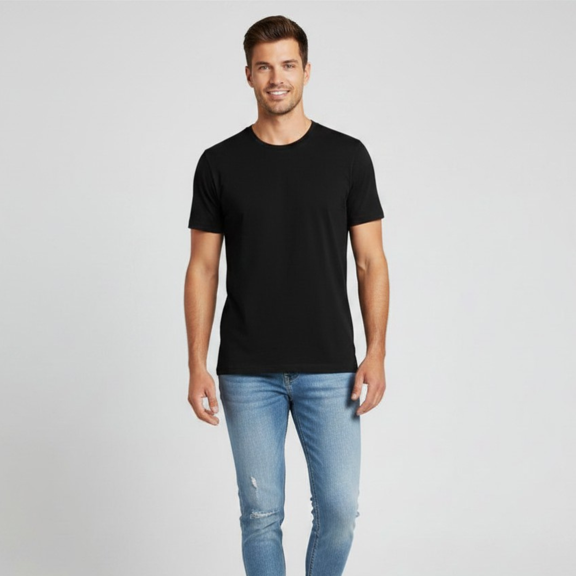 Man wearing a black t-shirt and light blue jeans on a gray background